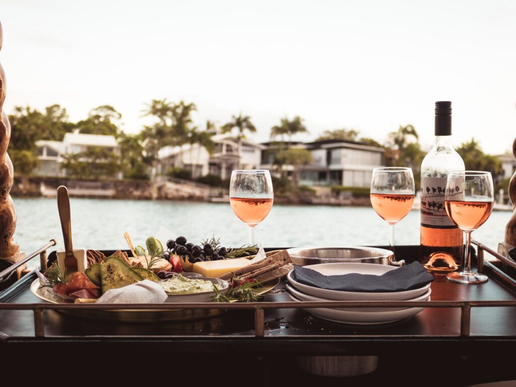 Outdoor dining table with rosé wine and a gourmet platter, overlooking waterfront homes.